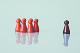 A brown chess piece set apart from a group of red ones to demonstrate leadership.